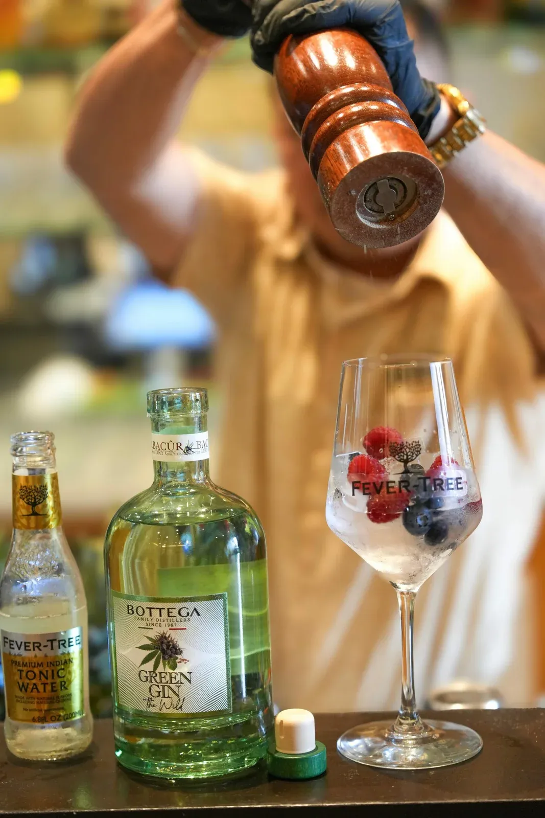 A gin cocktail being finished beside bottles of Bottega The Wild gin and Fever-Tree tonic