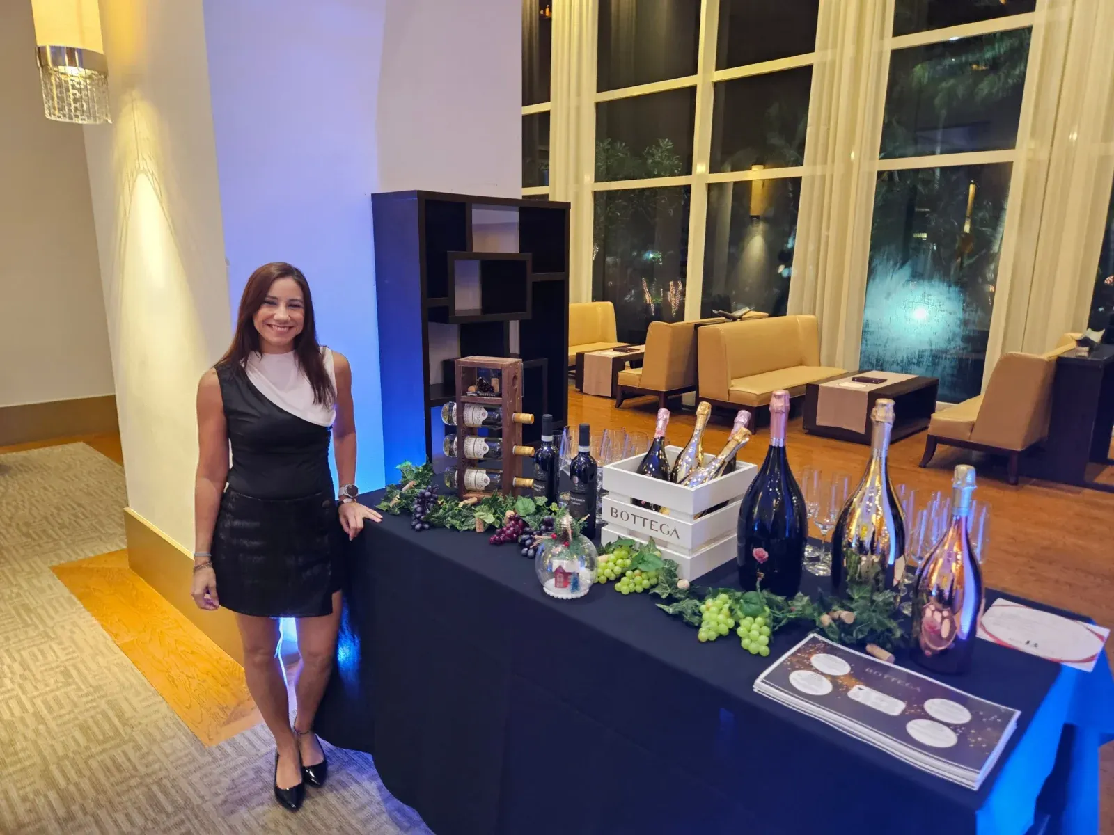 A host beside a table of Bottega sparkling wines dressed with grapes
