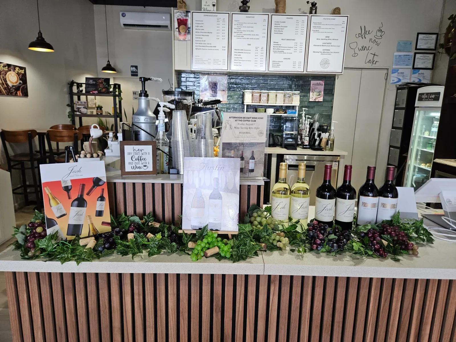 Wines displayed with grapes and greenery on the counter at The Coffee Club