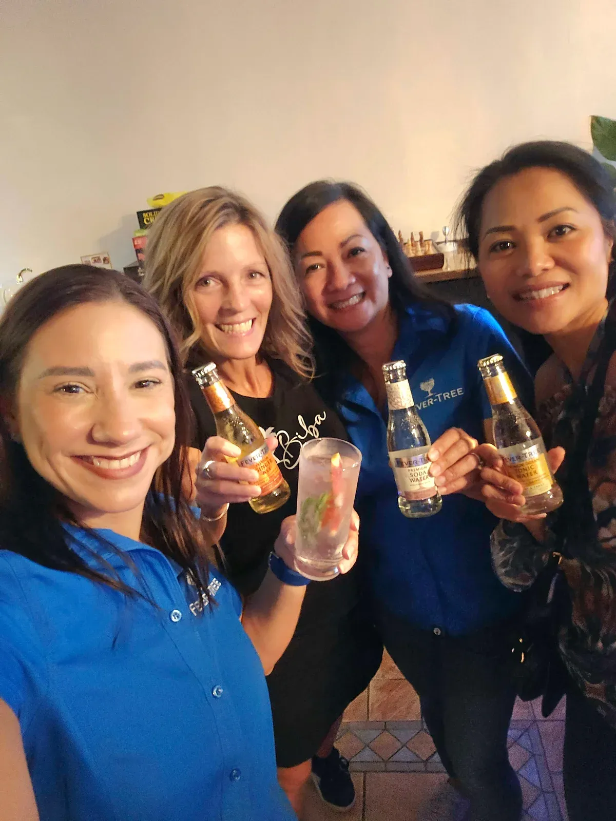 Four guests at Biba Bar holding Fever-Tree tonic bottles and a gin and tonic