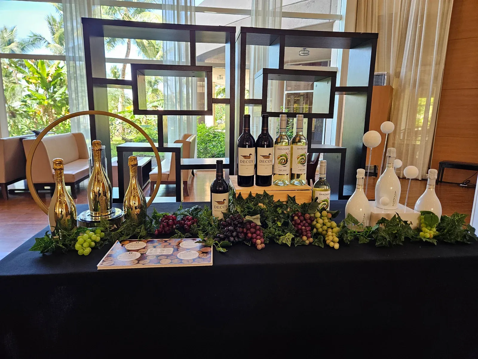 Bottega gold sparkling bottles and red wines on a black table dressed with grapes